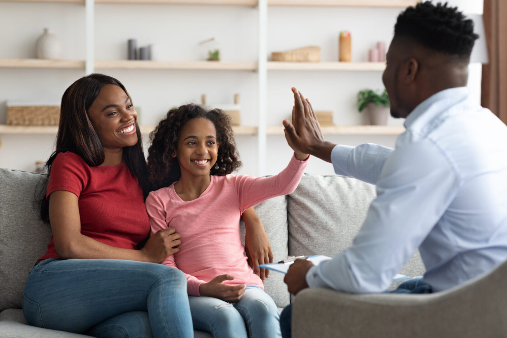 A man giving two women high fives in front of them.