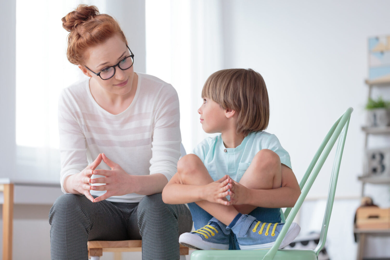 A woman and child sitting on the floor talking.