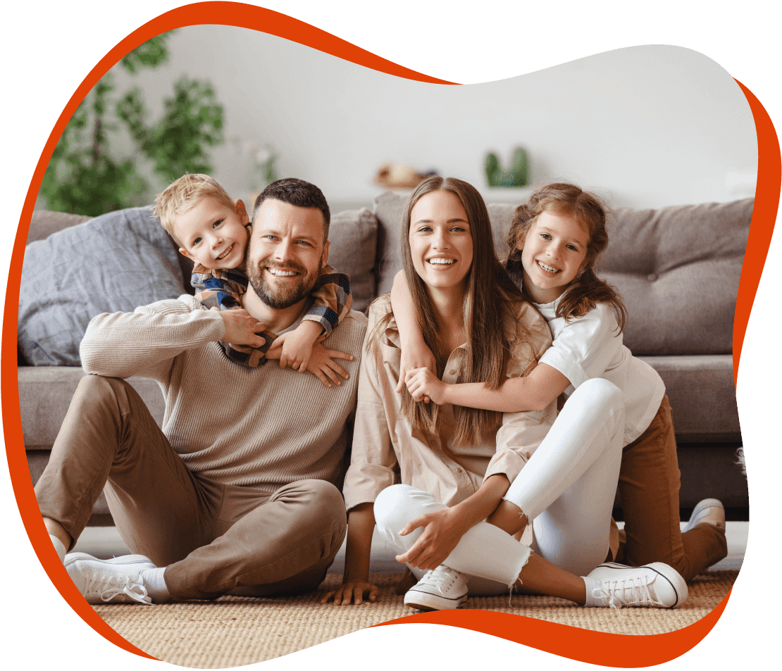 A family sitting on the floor in front of a couch.