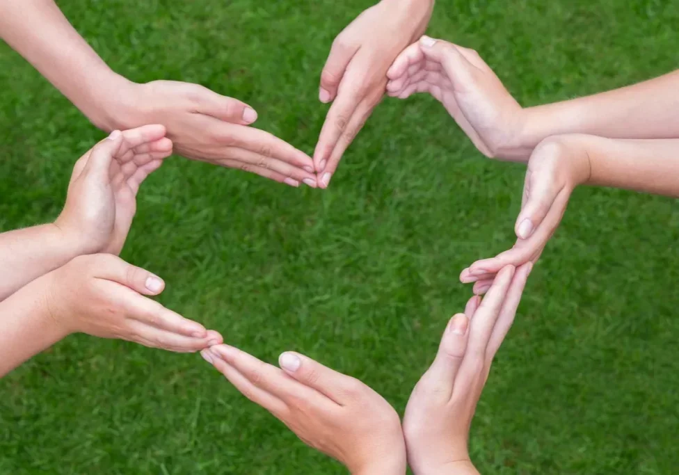 A group of hands are forming the shape of a heart.